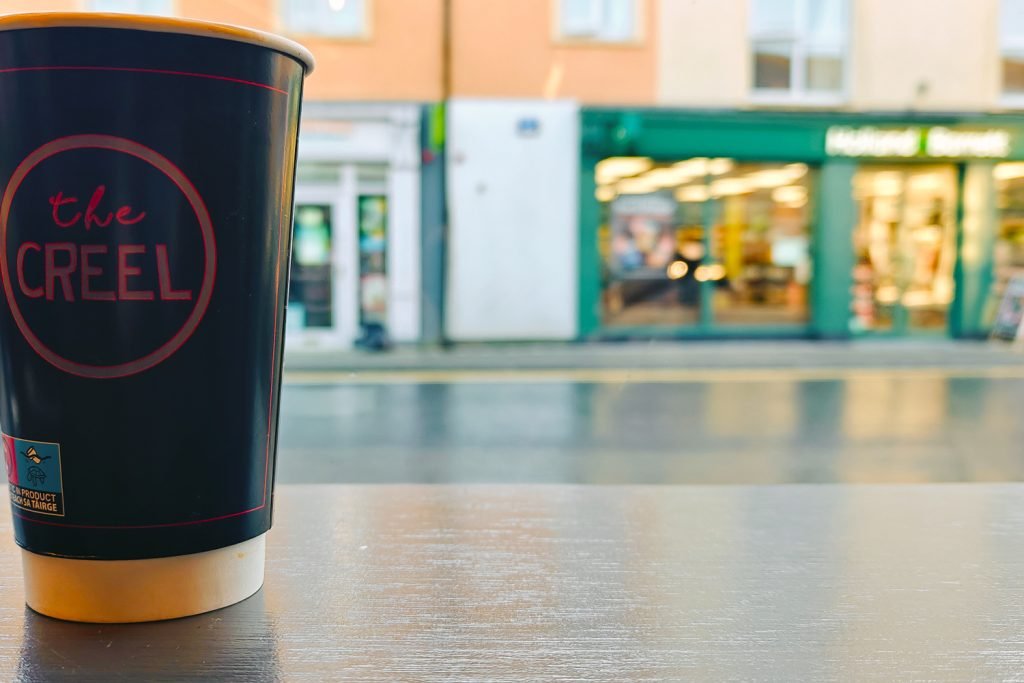 A paper coffee cup on a counter with view of the street outside