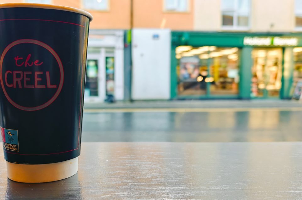 A paper coffee cup on a counter with view of the street outside