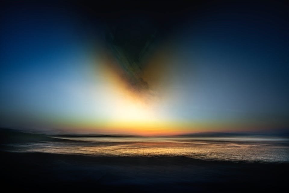A soft-focus sunset over the sea, with warm light spreading low along the horizon beneath a dark, smoky burst of cloud rising into a deep blue sky.